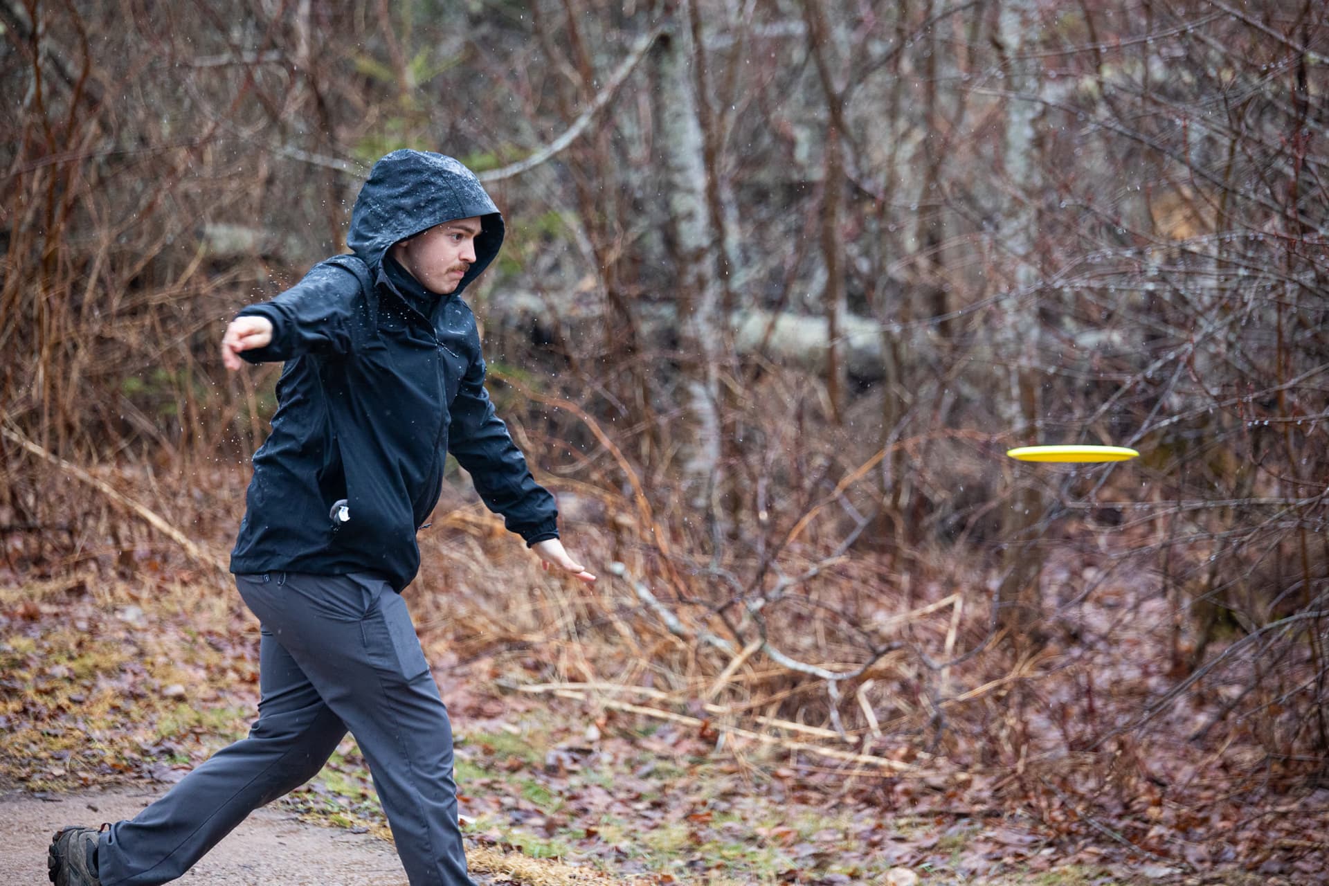 Rainy round throwing a yellow driver through bare trees