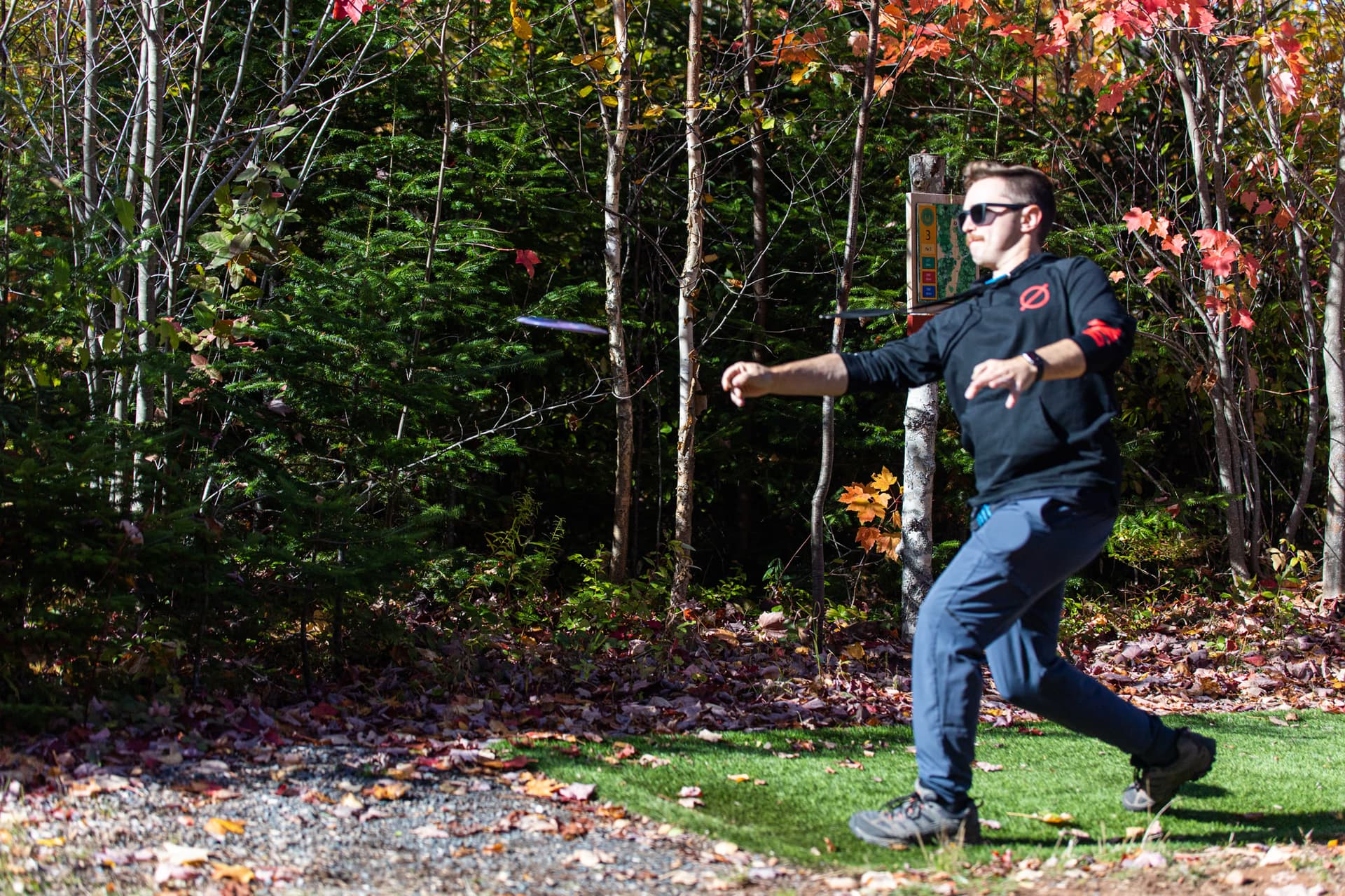 Tournament tee shot leaving the pad into autumn forest